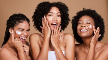 Skincare, beauty and black women, friends and face cream in studio on brown background. Group portrait, smile and happy models apply facial lotion or cosmetics product for moisturizing healthy skin.