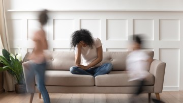 Frustrated stressed single african mom having headache feel tired annoyed about noisy active kids playing at home, upset disturbed black mother fatigued of difficult disobedient misbehaving children